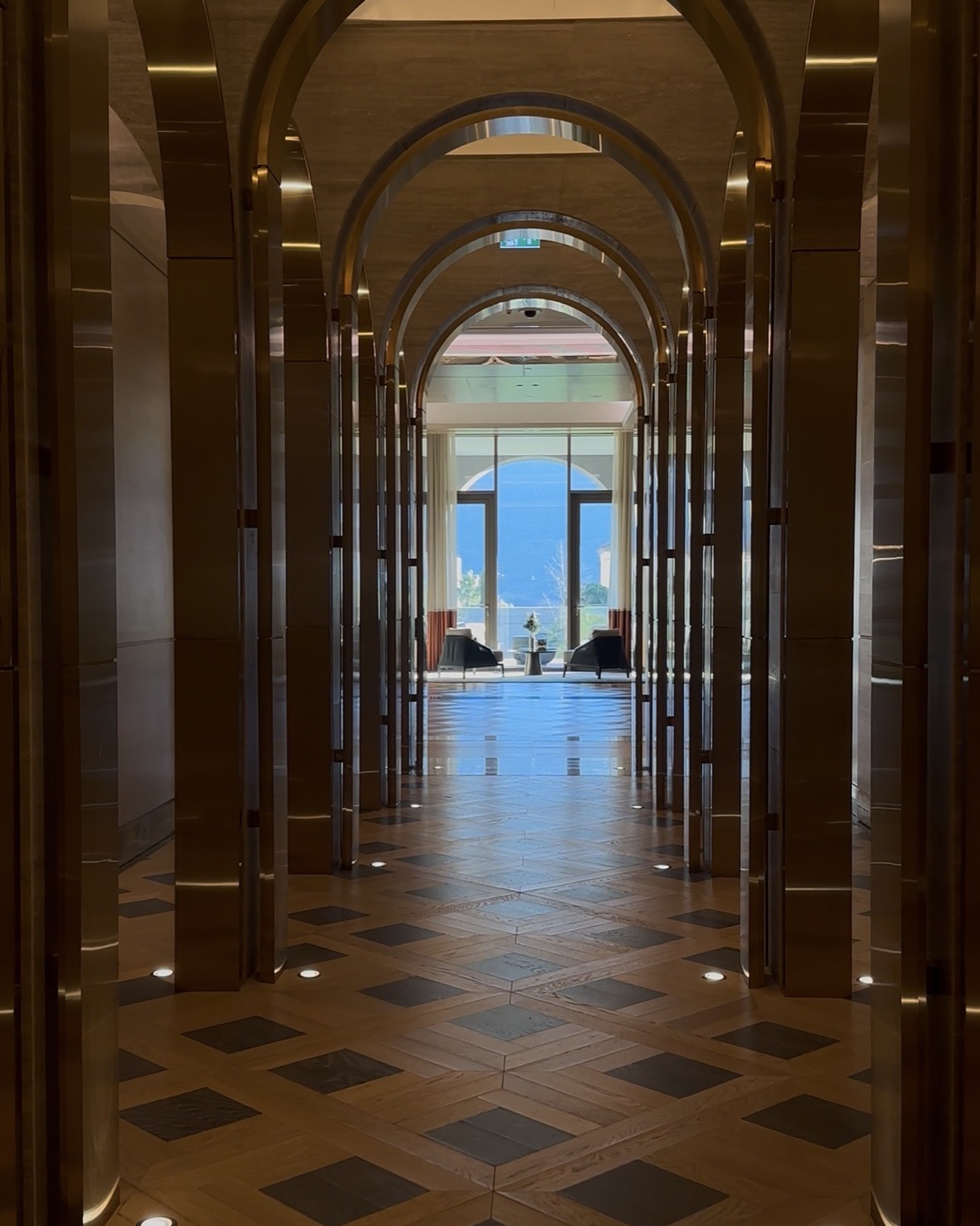 A dramatic arched hotel corridor leading towards a mountain view