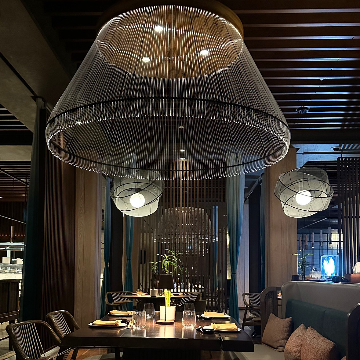 A softly lit restaurant table beneath a statement pendant light