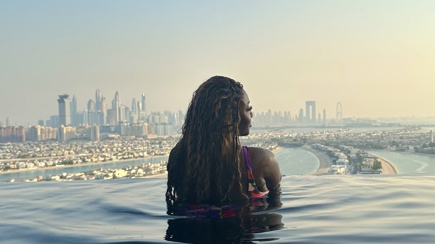 Valerie overlooking a city skyline from an infinity pool